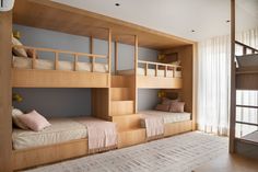 bunk beds in a room with white curtains and wooden flooring, along with a rug on the floor