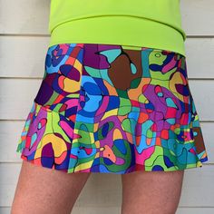 "This new style skort has a flat front panel with a ruffle that starts on the side and wraps around the back. Designed with a wide waistband that magically diminishes \"muffin top\" and a coordinating short beneath with a pocket on the side. It's the most flattering and comfortable skirt you will ever wear! Sizing:  XS/2, S/4-6, M/6-8, L/10-12, XL/14-16 Each item is handmade and there can be slight differences, however skirt lengths are generally: XS/13.5\", S/13.5\"-14\", M/13.5\"-14\", L/14.5\"-15\", XL/15\" Made with swimsuit fabric, it stretches in all the right places and always keeps it shape. Completely machine washable and dryable. This item may be returned for a full refund. Buyer must pay return shipping. This item is made to order and will take 1-2 weeks before shipping.  The vi Green Casual Tennis Skirt, Casual Green Tennis Skirt, Green Short Tennis Skirt With Built-in Shorts, Green Tennis Skirt With Built-in Shorts, Fitted Tennis Skort With Elastic Waistband, Multicolor Summer Bottoms For Cheerleading, Green Mini Skort With Built-in Shorts, Fitted Tiered Skort With Built-in Shorts, Summer Cheerleading Skirted Skort