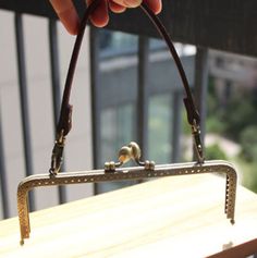 a person holding a small purse on top of a wooden table next to a window