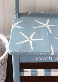 a blue chair with white starfish painted on it and the words beach day written on it