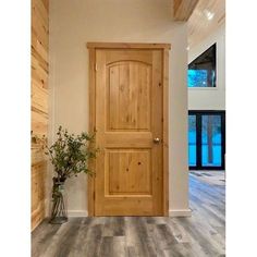 a large wooden door sitting inside of a living room next to a vase filled with flowers