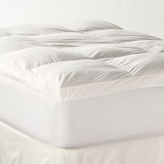 an unmade bed with white sheets and pillows on it's bottom layer,