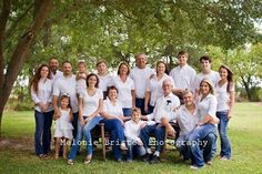 a large group of people posing for a photo in front of a tree and grass area