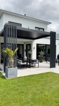 a modern house with an open patio and dining area in the back yard, on a cloudy day