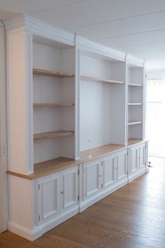 an empty room with white cabinets and wood floors