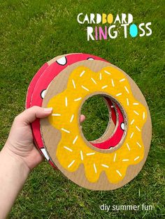 someone is holding up a cardboard ring tosser in the grass with a donut on it