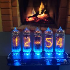 four blue glass clocks sitting on top of a black table next to a fire place