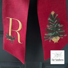 a red scarf hanging on the front door with a christmas tree and letter r embroidered on it