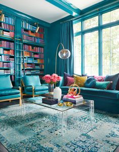 a living room filled with furniture and bookshelves covered in lots of colorful books