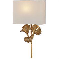 a lamp with a white shade on top of it and a gold leaf design around the base