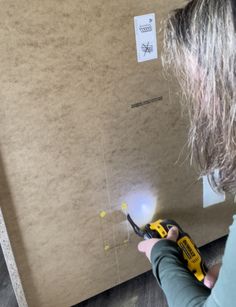 a woman using a power tool to cut out the wall