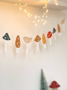 mushrooms are hanging on the wall next to a christmas tree and small trees in front of it