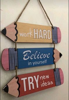 three wooden pencils hanging on a wall with the words work hard, believe in yourself and try new ideas