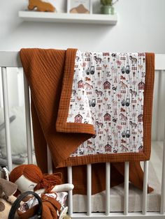 a baby crib with an orange blanket on it