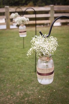 two mason jars with flowers hanging from them