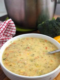 a white bowl filled with soup next to broccoli and an orange