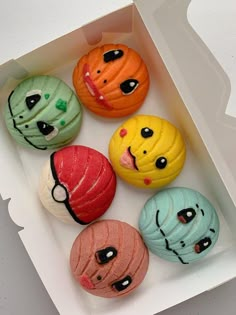 six different colored donuts in a box with faces painted on the top and bottom