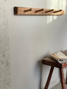 a wooden bench sitting in front of a wall mounted towel rack on the side of a white wall