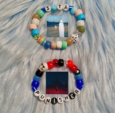 two bracelets with pictures and words on them sitting on a white fur covered surface