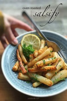 a blue plate topped with french fries covered in parsley next to a lemon wedge