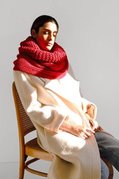 a woman sitting in a chair wearing a red scarf