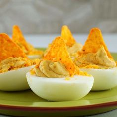 deviled eggs topped with cheese and chips on a green plate