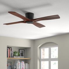 a ceiling fan in a living room next to a book shelf with books on it