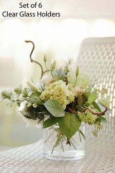 a vase filled with white and green flowers on top of a wooden table next to a chair