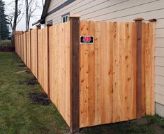 a wooden fence with a red and white sticker on it's side in front of a house