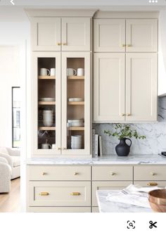 a white kitchen with marble counter tops and cabinets in the center, along with a vase on the island