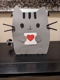 a gray cat with a red heart on it's nose sitting on top of a table