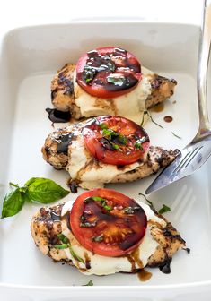 grilled chicken with tomatoes and mozzarella sauce on a white plate next to a knife