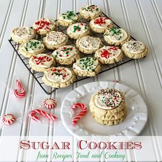 sugar cookies with white frosting and sprinkles on a plate next to a cooling rack