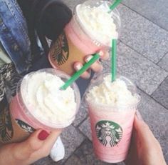 three starbucks drinks in plastic cups with green straws on the top and one being held up by someone's hand