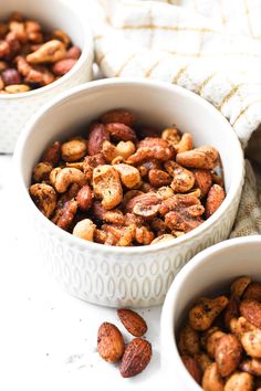 two white bowls filled with nuts on top of a table