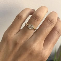 a woman's hand wearing a gold ring with two small diamonds on the band