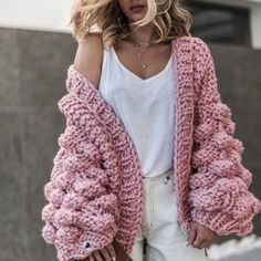 a woman wearing white shorts and a pink knitted cardigan