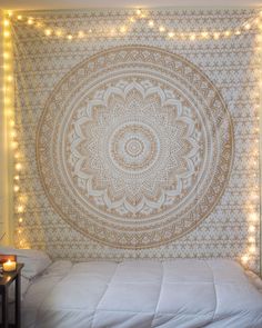 a large tapestry hanging on the wall above a bed in a room with string lights