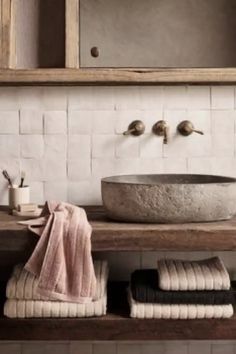 a bathroom sink sitting under a mirror next to a wooden shelf with towels on it