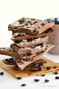 a stack of chocolate bars sitting on top of a wooden cutting board next to coffee beans