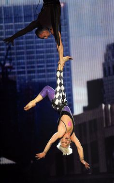 two acrobats doing tricks in the air with their hands on each other