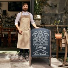 a man in an apron standing next to a sign