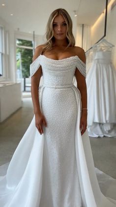 a woman in a white wedding dress posing for the camera