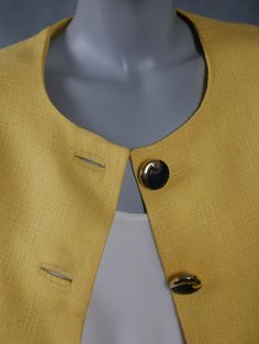 This 1990s Italian vintage short-sleeve summer blazer is a beautiful yellow color, and is crafted from a woven viscose that gives the appearance of fine linen. The professional jacket has a round neckline and padded shoulders, and closes in the front with five black and gold buttons. One black and gold button decorates each sleeve edge. The blazer features figure-enhancing contour lines on the front and the back, and has a fitted waistline that then falls with a slight flare. The jacket is lined Contour Lines, Summer Blazer, Vintage Short, Fine Linen, 1960s Fashion, European Vintage, Womens Blazers, Plaid Blazer, Double Breasted Blazer