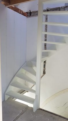 there is a white staircase going up the side of a wall in an unfinished room