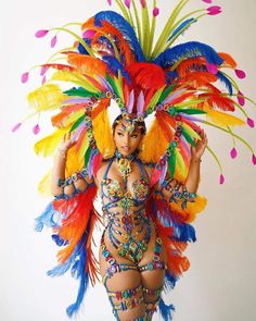 a woman in a colorful costume with feathers on her head and hands behind her back