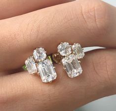 a woman's hand holding two diamond earrings