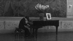 a man sitting at a piano in front of a painting