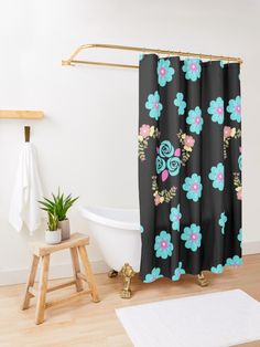 a bathroom with a flower shower curtain next to a white bath tub and wooden stool