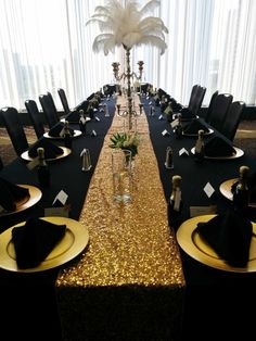 the table is set with black and gold plates, silverware, and centerpieces